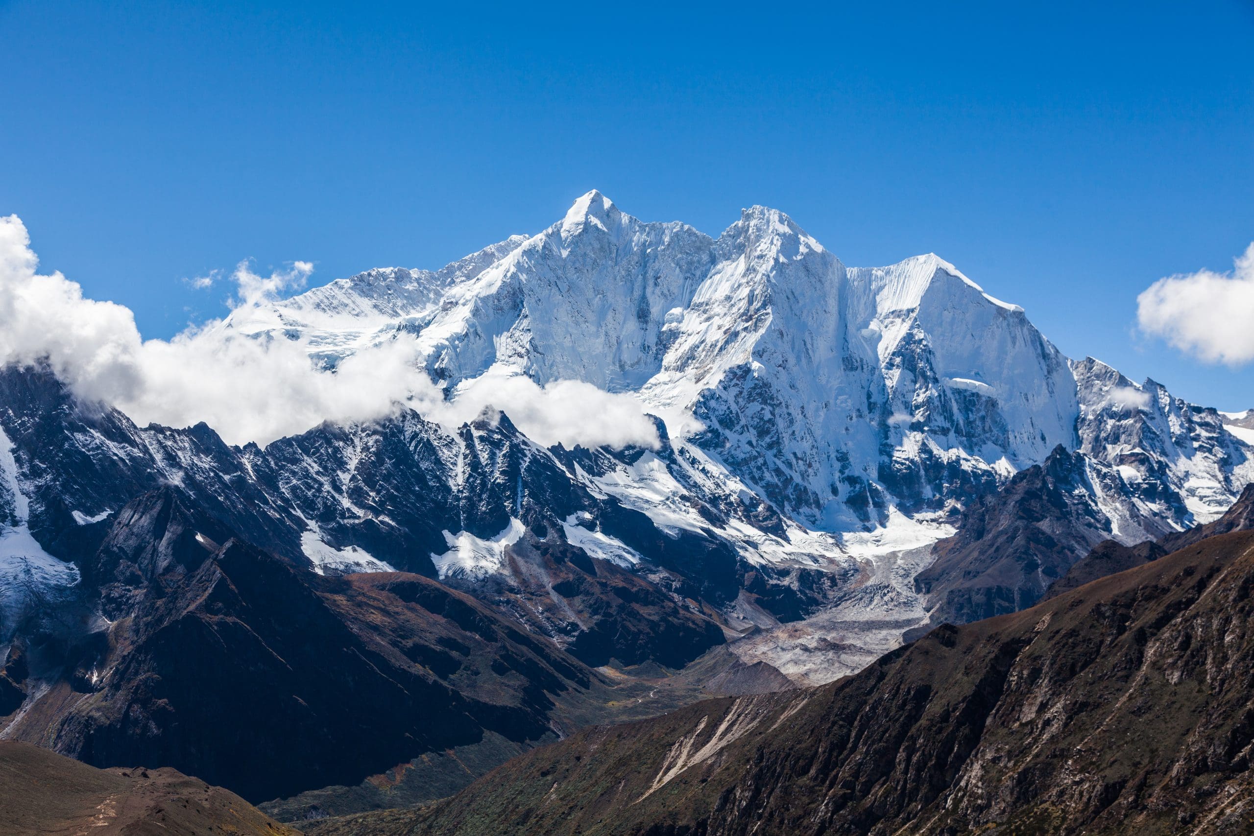 Majestic snowy mountain peak against a clear blue sky, showcasing its grandeur from afar.
