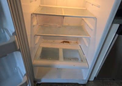 Empty refrigerator interior with noticeable food stains and spills before getting a deep clean.