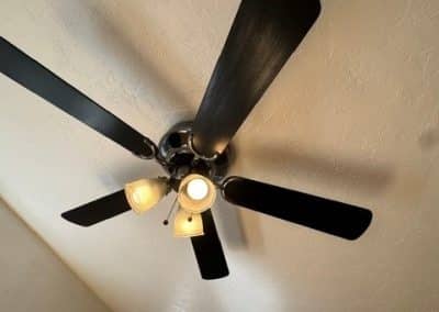 A clean, dust-free dark wood ceiling fan with illuminated light fixtures after professional home detailing.